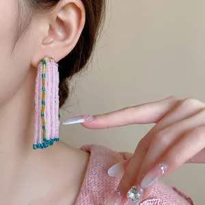 Boucles d'oreilles pendantes à pompons de perles roses portées par un mannequin
