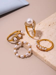 Vue détaillée d'un ensemble de quatre bagues dorées avec perles et oxydes de zirconium