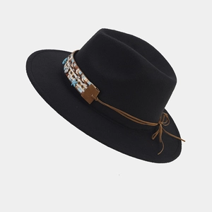 Detalle de sombrero fedora de lana negra con banda étnica tejida y dijes de estrella azul