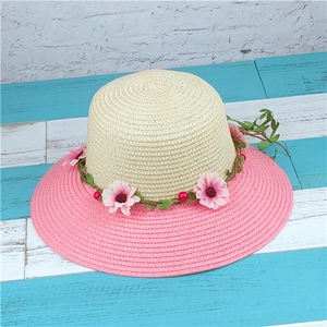 Close-up of wide brim straw sun hat with pink floral wreath and bicolor woven texture
