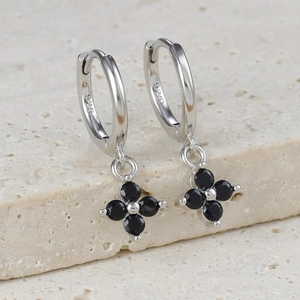 Macro detail of S925 sterling silver huggie earrings with black clover flower charms
