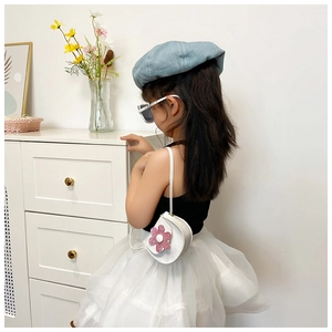 Detail shot of a small white flower saddle bag worn by a young girl as a trendy accessory
