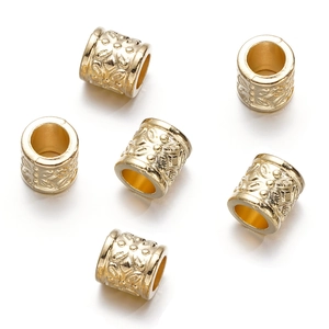 Detailed macro view of gold hollow-out floral pattern cylinder beads for DIY jewelry