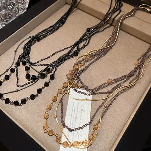 Detail of multilayer crystal beaded necklaces in gold and black on a beige velvet display