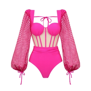 Détail d'un maillot de bain corset rose vif avec maille et manches lanterne en dentelle