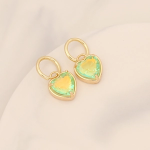 Macro shot of 18K gold heart earrings featuring yellow-green gradient gemstones