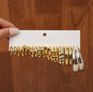 Macro shot of a 20-piece gold geometric hoop earring set with various textures on a white card