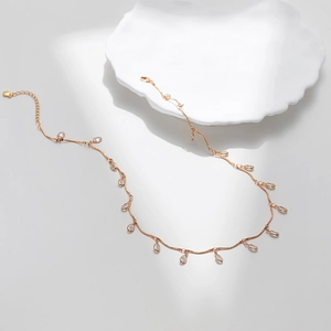 Detailed close-up of 18K gold plated necklace with zircon charms on a white ceramic plate