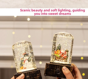 Close-up of glowing Christmas snow globe with Santa and Snowman figures in warm light