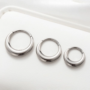 Polished silver G23 titanium hoop earrings set in three sizes on white leather texture