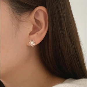 Close-up of elegant flower shaped stud earrings with pearls worn on model ear