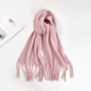 Flat lay of soft pink mohair scarf with fringe tassels and a knotted design layout