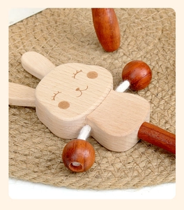 Close-up of a rabbit-shaped wooden baby rattle and teether toy on a woven mat