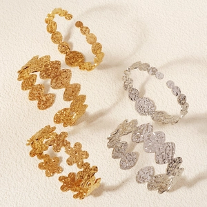 Detail of metal cuff bangles featuring hammered texture and lava effect in gold and silver