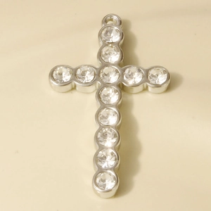 Macro view of silver 304 stainless steel cross pendant with sparkling crystal inlay