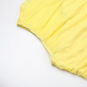 Détail de la robe en mousseline jaune montrant la taille élastique froncée et les coutures