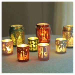 Close-up of assorted glass Christmas candle holders with reindeer and forest patterns