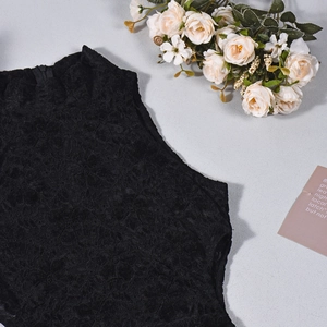 Close-up of intricate black floral lace pattern on a sleeveless high-neck bodysuit