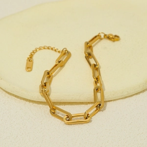 Détail du bracelet chaîne trombone doré avec un charm lettre D et un fermoir mousqueton