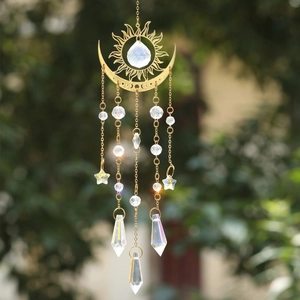 Detail of golden sun and moon suncatcher with large AB crystals and stars hanging in a garden