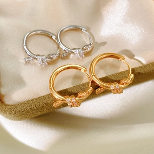 Close-up of gold and silver knot hoop earrings with micro-set zircon stones on silk