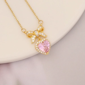 Pink heart pendant necklace with butterfly bow detail on a white ceramic plate