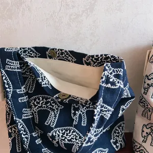 Detail of navy canvas bag with white animal embroidery and retro metal magnetic clasp