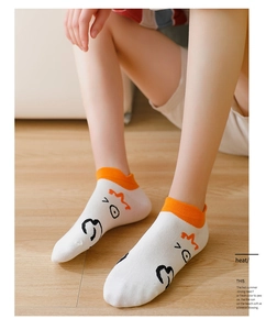 Close-up of white cotton ankle socks with cute cartoon duck faces and orange ribbed cuffs