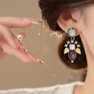 Detail of vintage earring featuring colorful resin gemstones and crystal floral accents