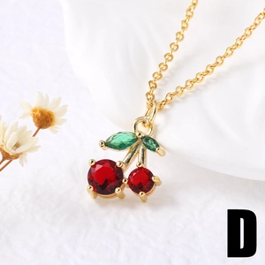 Macro shot of gold-plated cherry pendant necklace with red crystals on white background