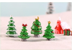 Macro shot of miniature resin Christmas trees with colorful holiday decorations on sand