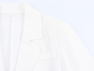 Detailed close-up of a white blazer collar showing linen texture and size S label