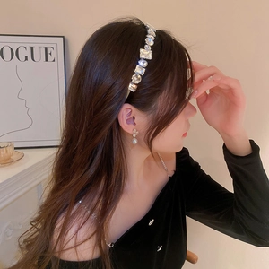 Detailed side view of sparkling geometric crystal headband and white floral earrings