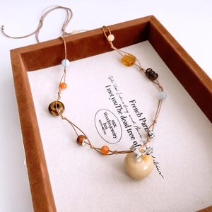 Detailed view of handmade tiger eye stone apple pendant on woven necklace string