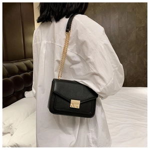 Side view of the black leather crossbody bag with elegant gold chain strap on model