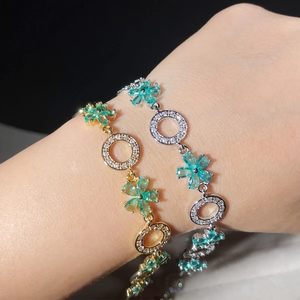 Detailed view of flower-shaped bracelets in gold and silver with zircon stones on wrist