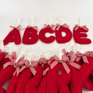 Detail of red felt alphabet ornaments with ribbon, bow, and small gold bell decorations