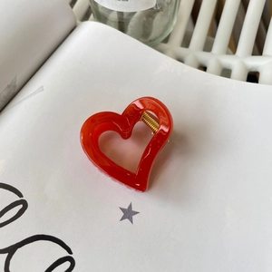 Elegant red heart-shaped hair claw clip with gold spring on a minimalist white background
