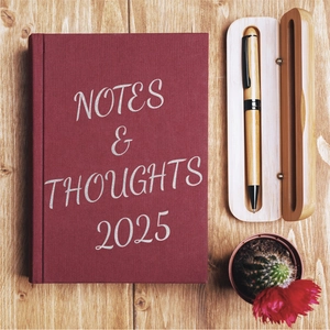 Macro shot of 2025 burgundy fabric notebook and wooden pen box on a wooden desk