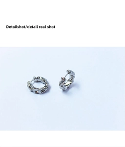 Gros plan de boucles d'oreilles créoles argentées avec texture lave et fermoir charnière