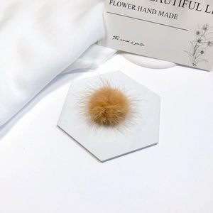 Macro detail of a soft khaki mink fur pompom accessory on a marble coaster