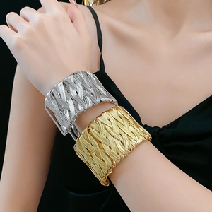 Detail of vintage twisted woven cuff bracelets in gold and silver on a model's wrist