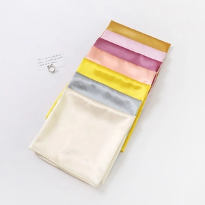 Detailed view of colorful satin silk square scarves with shiny finish stacked on a white surface