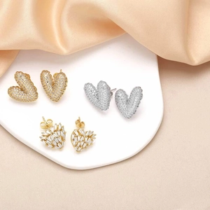 Sparkling gold and silver heart stud earrings with cubic zirconia on elegant satin background
