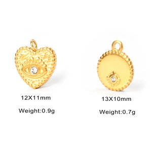 Detail view of gold titanium steel heart and evil eye charms with white crystal accents