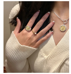 Detail of vintage bicolor coin necklace and ring set on minimalist knit sweater