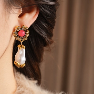 Close-up of vintage flower earrings with pink gems and baroque pearls on model