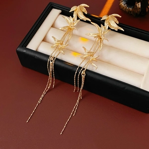 Detail of gold bamboo leaf tassel earrings displayed in a premium jewelry gift box