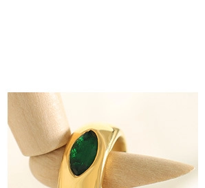 Detail of gold-tone cross ring with marquise green stone on a wooden mannequin hand