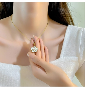 Close-up of elegant camellia flower pendant necklace with gold chain worn by model